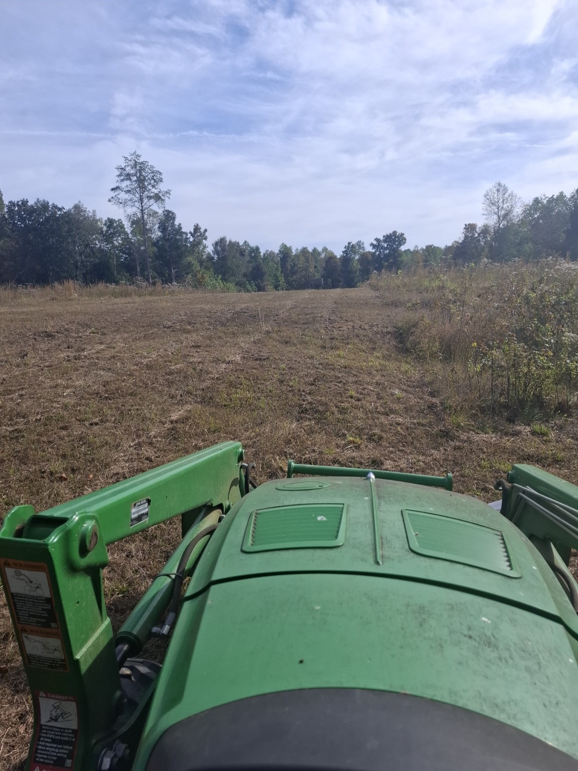 Green tractor bush hogging a field