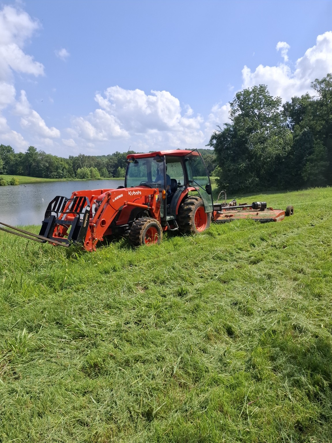 Kubota tractor working beside a pond